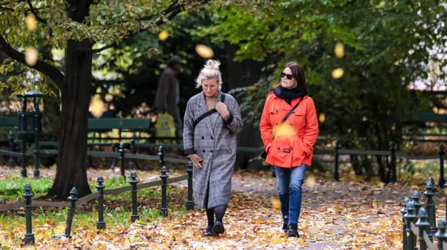 Dwie kobiety spacerują po parku jesienią