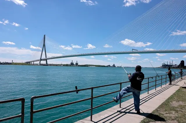 Personas pescando en un día despejado, bajo el puente Gordie Howe