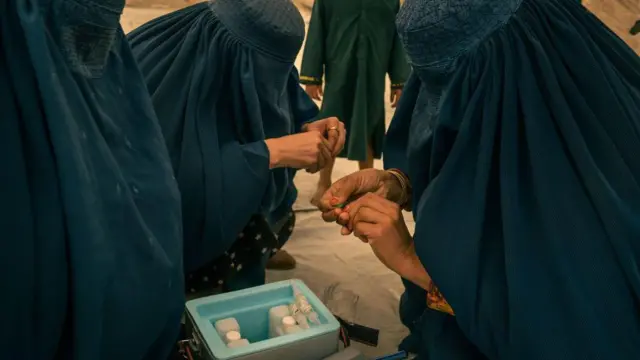 واکسیناتور افغان در حال آماده‌سازی واکسن‌های فلج اطفال در گذرگاه مرزی تورخم نوامبر ۲۰۲۳