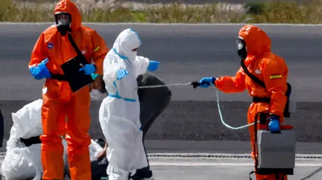 Personal sanitario rocía con un líquido a algunos de los evacuados.