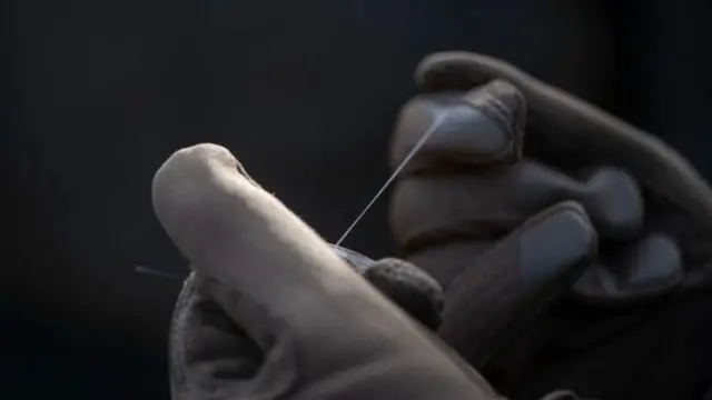 Руки тримають оптоволоконну нитку