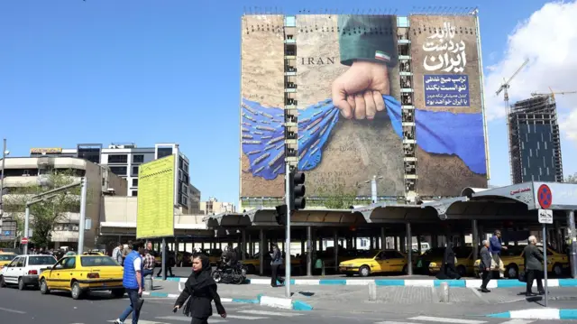 Огромный плакат на тегеранской площади с кулаком, сжимающим ткань, которая символизирует Ормузский пролив.