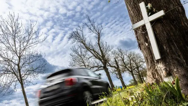 Carro passando sobre cruz memorial