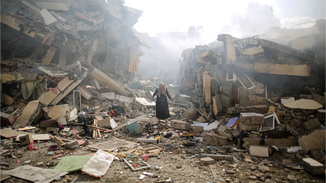 Mulher caminhandoloteriaonlinemeio a escombros na CidadeloteriaonlineGaza