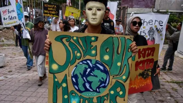 Pegiat lingkungan membawa poster selamatkan bumi dari krisis iklim.