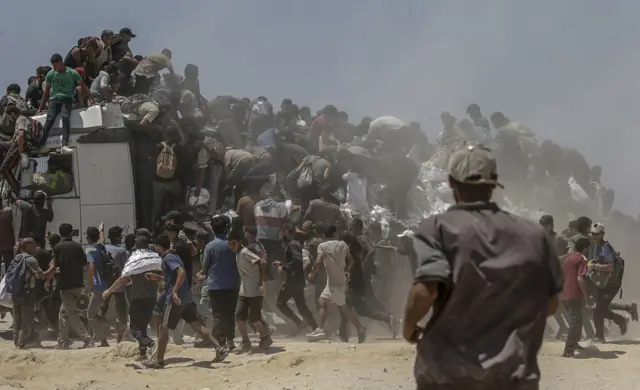 فلسطينيون يحاولون الحصول على أكياس دقيق من شاحنة مساعدات بالقرب من نقطة توزيع المواد الغذائية، شمال قطاع غزة، 27 يوليو 2025.