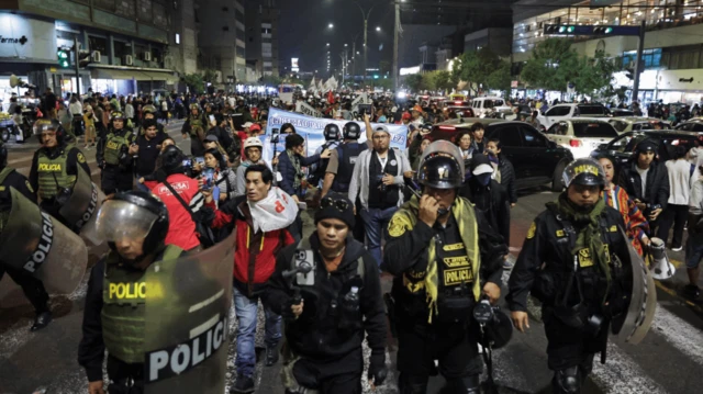 Agentes de policía caminan junto a los manifestantes que participan en una marcha organizada por el colectivo juvenil "Generación Z" para expresar su descontento por una controvertida reforma de las pensiones.