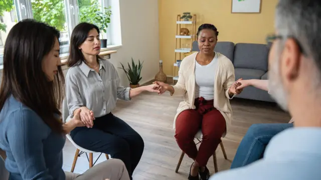 በክብ ቅርጽ ተቀምጠው እጅ ለእጅ የተያያዙ ሰዎች