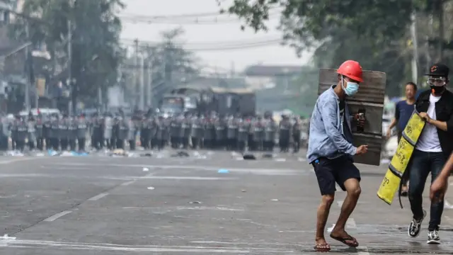 Protesters retreat in front of a line of police