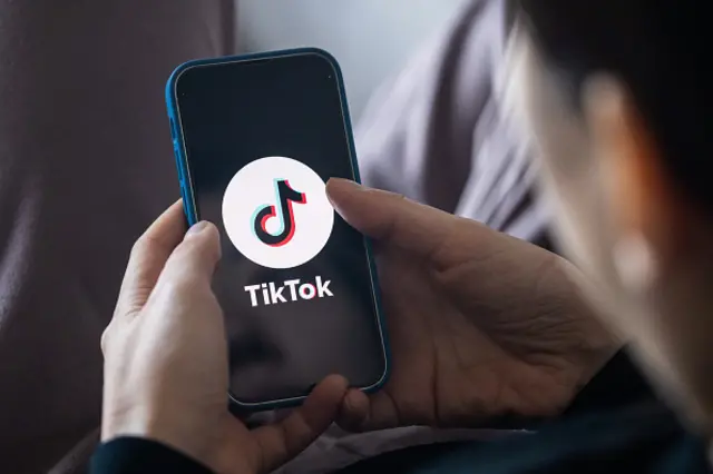 Pessoacupons da estrela betcostas usando celular, que mostra logo do TikTok