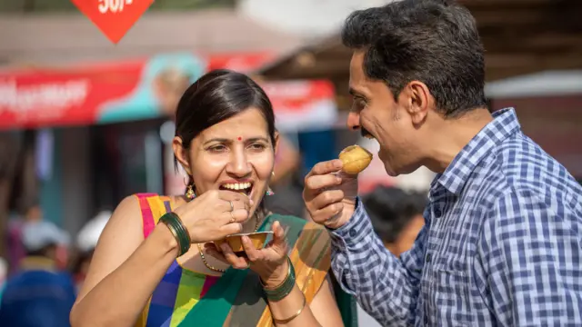 एक महिला आणि पुरुष पाणीपुरी खाताना