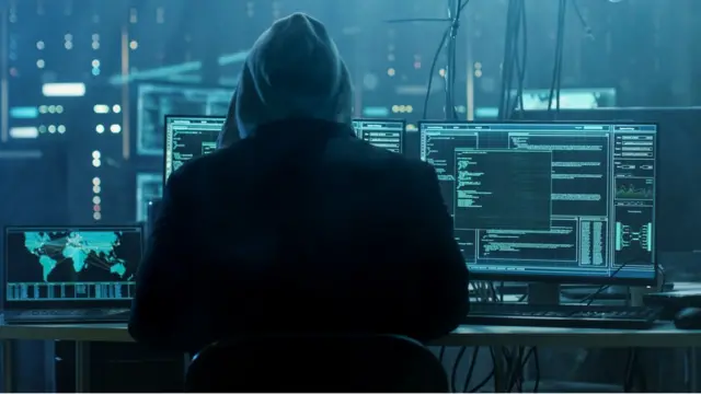 Criminal hacker with multiple computer screens