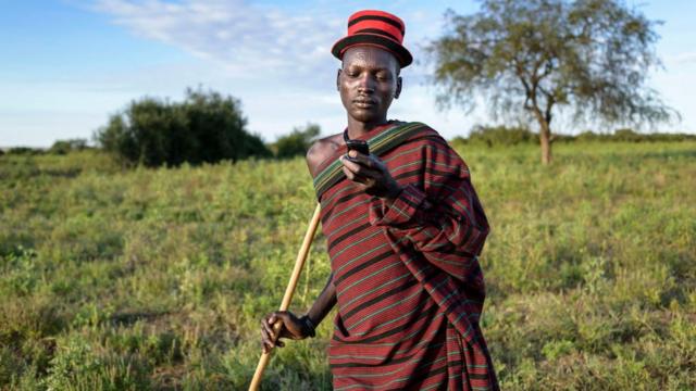 Ugandan farmer looking at phone in a field