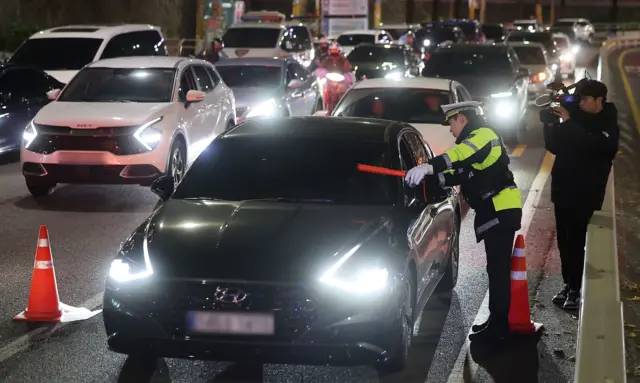 교통안전계 경찰이 서울 관악구의 한 도로에서 검은색 차량을 멈추게 한 뒤 0연말연음주·약물운전 특별단속을 하고 있다