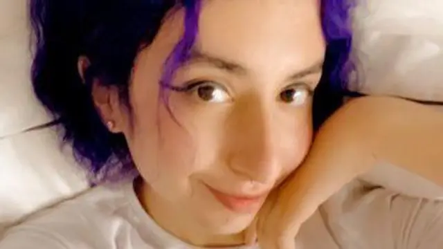 إيدن بشعر بنفسجي تنظر للكاميرا وتبتسم