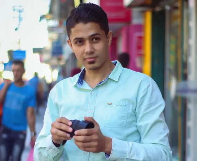Mohamed Alaswed holding a camera lens in a street