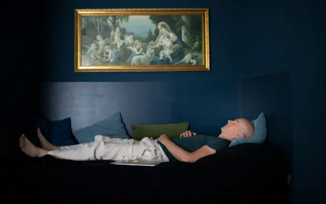 Людина спить у темній кімнаті під картиною