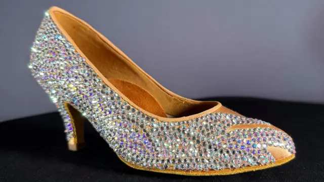 Un zapato de tacón brillante para bailarina. Es marrón claro y tiene muchos destellos.