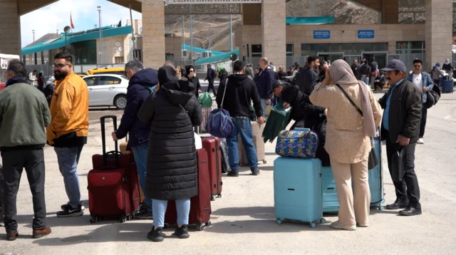 Van'da sınır kapısında çok sayıda kişi bavullarıyla bekliyor. Çoğunu arkaları dönük şekilde görüyoruz.