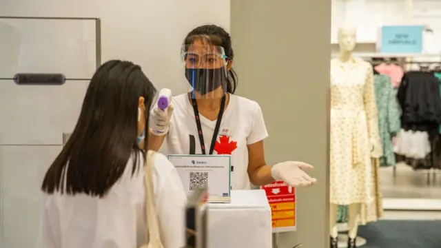 Tại mọi cửa tiệm, khách hàng đều phải đo nhiệt độ trước khi được bước vào trong. Cửa tiệm H&M tại Siam Paragon Mall, Bangkok, hôm 17/5