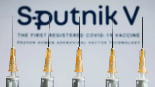 Syringes in front of a poster for Sputnik