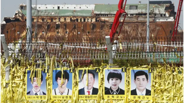 (캡션) 인양된 세월호 앞에 걸려있는 미수습자 5명의 사진