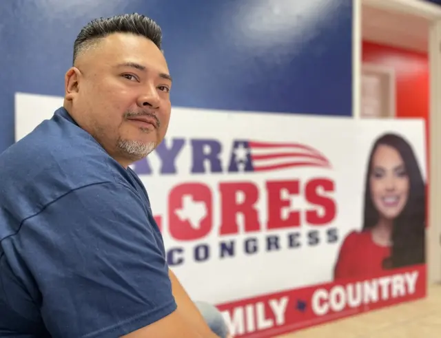 El pastor James Ramirez, de la iglesia evangélica City Church de Harlingen, frente a un cartel de Mayra Flores, en octubre de 2022.