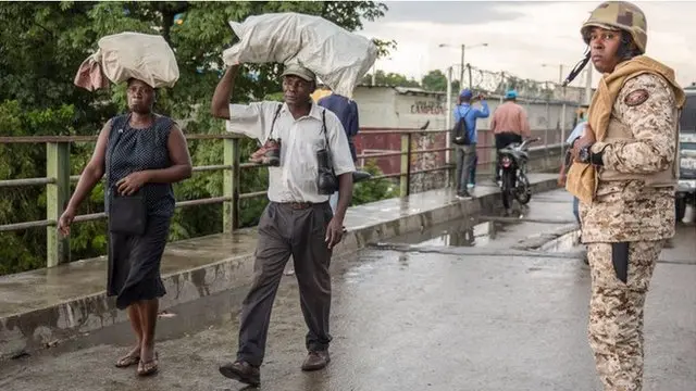 Oficial de la frontera, en puente, dos personas cruzan puente