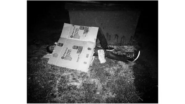 Hombre durmiendo en la calle tapándose con una caja de cartón.