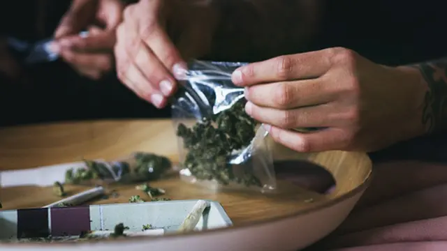 un homme roulant un joint de marijuana chez lui.