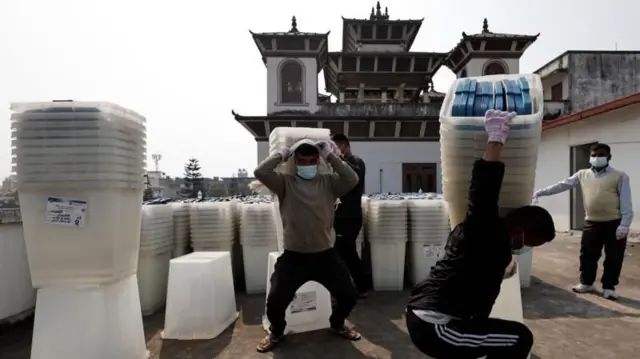 निर्वाचन आयोगको प्राङ्गणमा राखिएका खाली मतपेटिका बोक्दै केही कामदार 