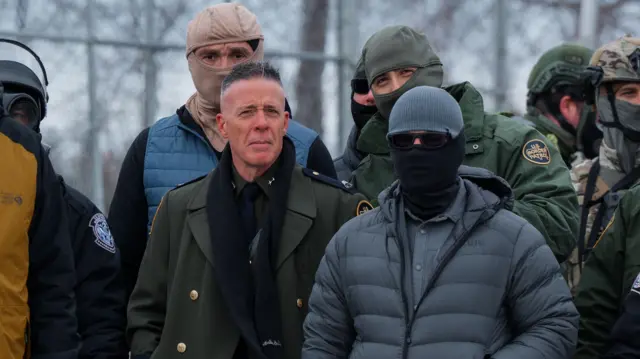   El jefe de patrulla de la Patrulla Fronteriza de EE.UU. UU., el agente Gregory Bovino (C), se encuentra entre agentes del Departamento de Policía de Minneapolis y agentes federales durante una protesta contra ICE frente al Edificio Federal Whipple, una base para operaciones federales de control migratorio, en Fort Snelling, Minnesota, EE.UU. UU., el 15 de enero de 2026. Foto de OLGA FEDOROVA/EPA/Shutterstock