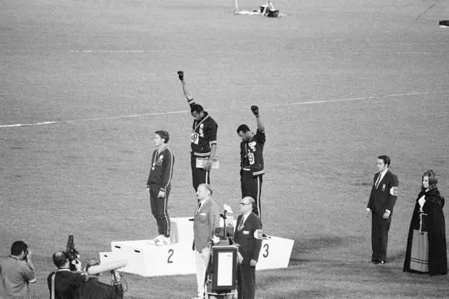 Tommie Smith e John Carlos no pódio com punhos levantados 