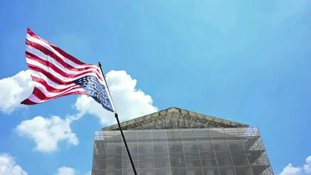Una bandera de Estados Unidos ondea del revés frente a la fachada de la Corte Suprema, cubierta por un andamio. 