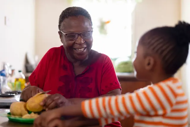 Femme d'âge mure qui coupe du pain en compagnie d'une jeune fille