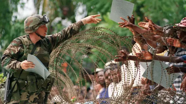 Un soldado estadounidense, custodiando el edificio del Parlamento haitiano, distribuye folletos prodemocracia escritos en criollo a los haitianos, el 28 de septiembre de 1994 en Puerto Príncipe.