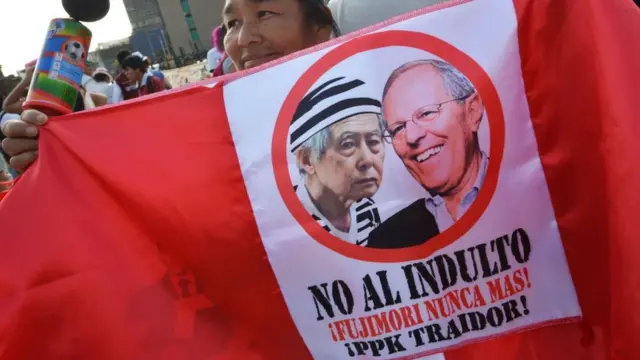 Un manifestante con una bandera peruana que contiene las fotos de Alberto Fujimori y PKK