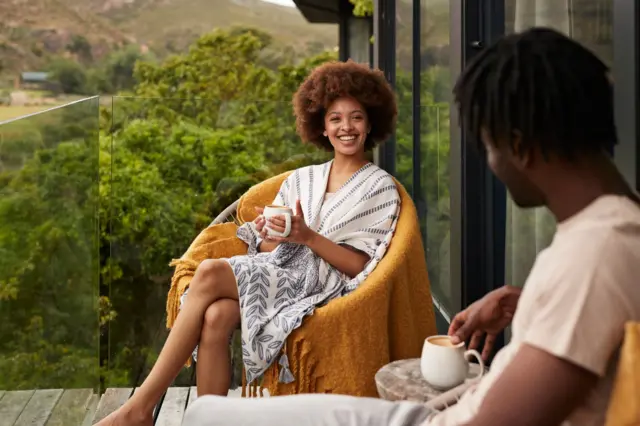 Femme heureuse avec une tasse de café regardant son petit ami sur le balcon.