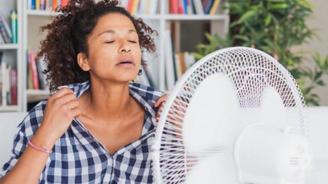 Mulher se refrescandosite aviator betanofrente a ventilador
