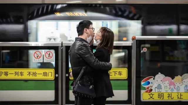 A couple kiss each other with their masks off while waiting for a train in Shanghai. 24 February