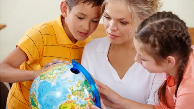 Mãe mostrando globo terrestre para os filhos