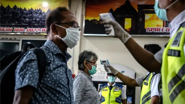Dois passageiros e dois agentes fazem triagem de temperatura