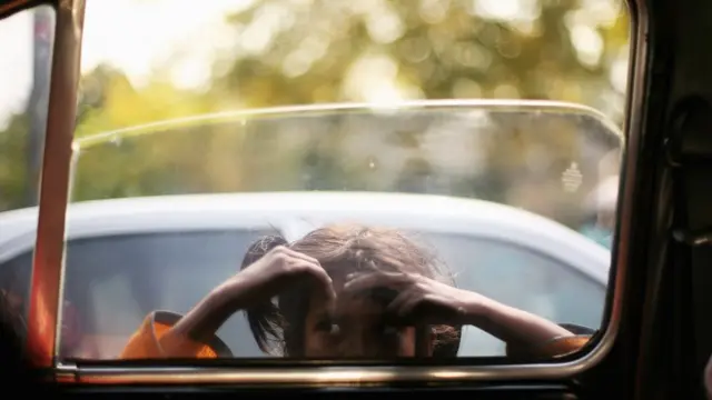 দিল্লিতে মেয়ে ট্যাক্সির জানলা দিয়ে উঁকি দিচ্ছে।