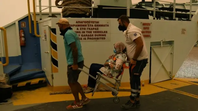 Una mujer es llevada al ferry en Evia.