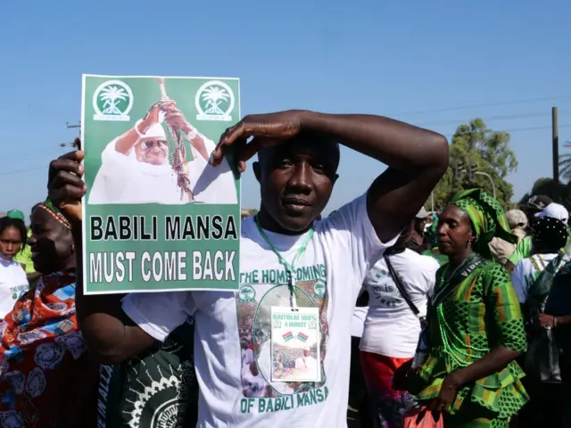 Un manifestant tient une affiche sur laquelle on peut lire "Babili Mansa (le surnom de Yahya Jammeh) doit revenir" lors d'une manifestation réclamant le retour de Yahya Jammeh, l'ancien président de la Gambie, à Sukuta, en Gambie, le 16 janvier 2020.