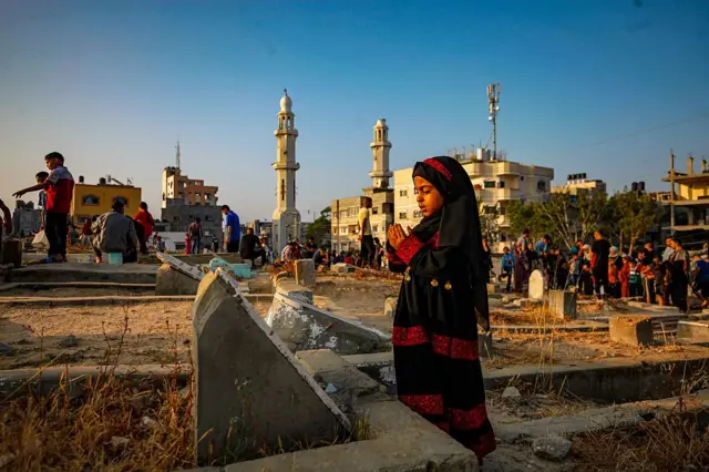 Palestinians of Nuseirat Camp visit the graves of their beloved ones in the cemetery amid the destroyed buildings on the occasion of the night before the Eid al-Adha in Gaza, Palestinian territories on June 6, 2025.