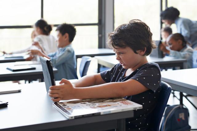 Criança com tablet em sala de aula