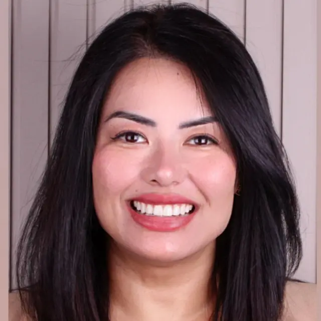 Viviana Makiyama sorrindo para foto, em frente a parede