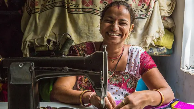 Seorang perempuan di Jodhpur, India, menjahit pakaian. 