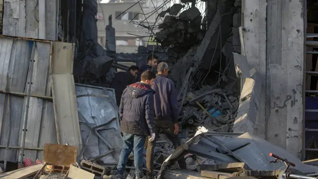 Unos hombres caminan entre los escombros de un edificio en Zeitoun, Gaza